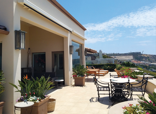 Retracted full cassette awning tucked against the fascia of a terrace overlooking the coast