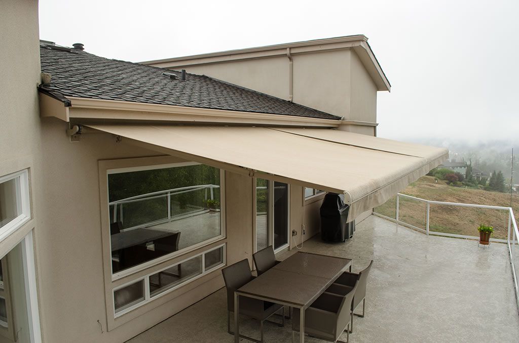 Retractable awning extended over a patio, showing the folding lateral arms and roof-mounted brackets