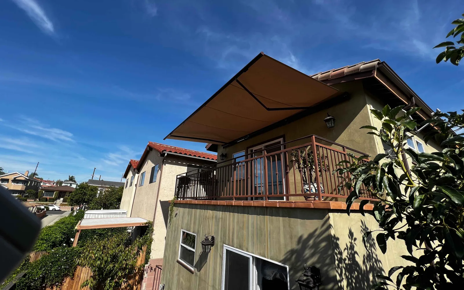 Tan retractable awning fully extended over a second-story balcony of a Southern California home