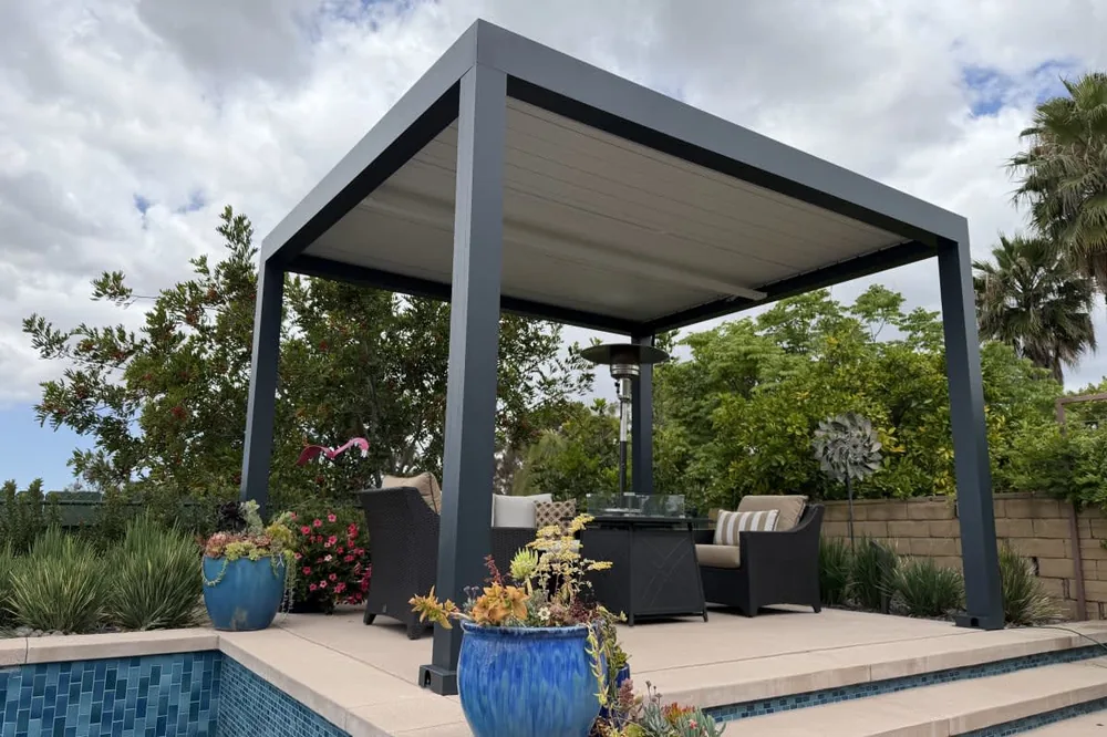 Freestanding Atlas louvered roof patio cover in Grafite with louvers closed over a poolside seating area