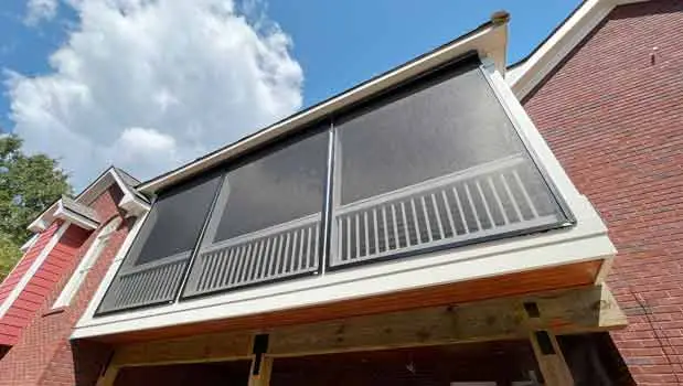 Close-up of exterior-grade motorized screen fabric deployed on a brick home