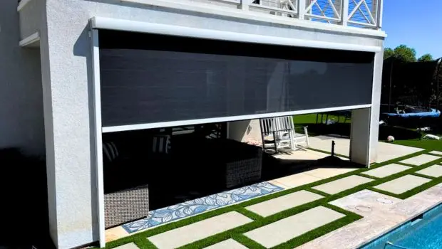 Motorized patio screen deployed beside a pool