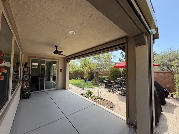 Motorized outdoor shade housing on a covered patio overlooking the backyard