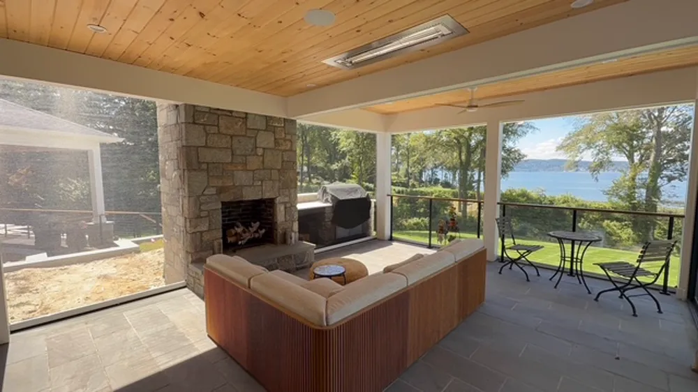 Motorized screen porch with stone fireplace overlooking a lake