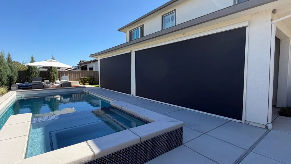 Motorized shade poolside on a two-story home, black mesh fabric