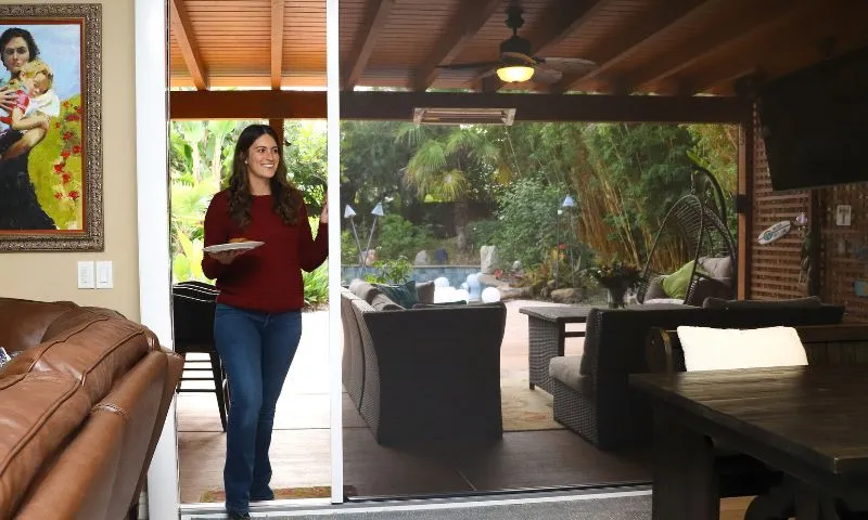 Motorized retractable screen covering a large bi-fold door opening on a modern home