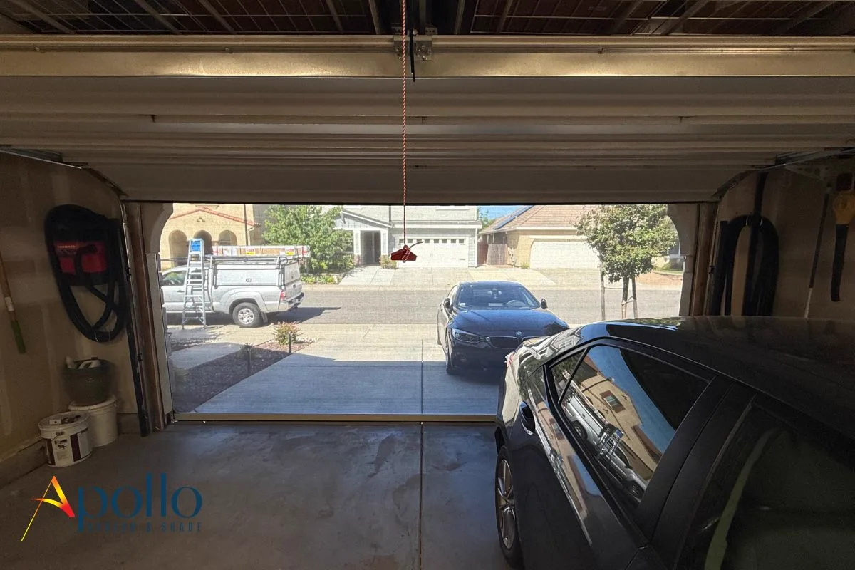 View out through a garage door screen — one-way daytime privacy mesh, seeing the driveway from inside